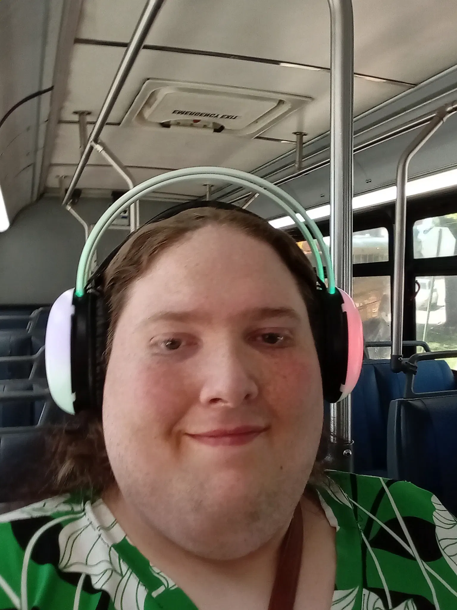 Selfie of a transgender woman wearing wireless LED Headphones, and a green kimono. She is looking at the camera and smiling